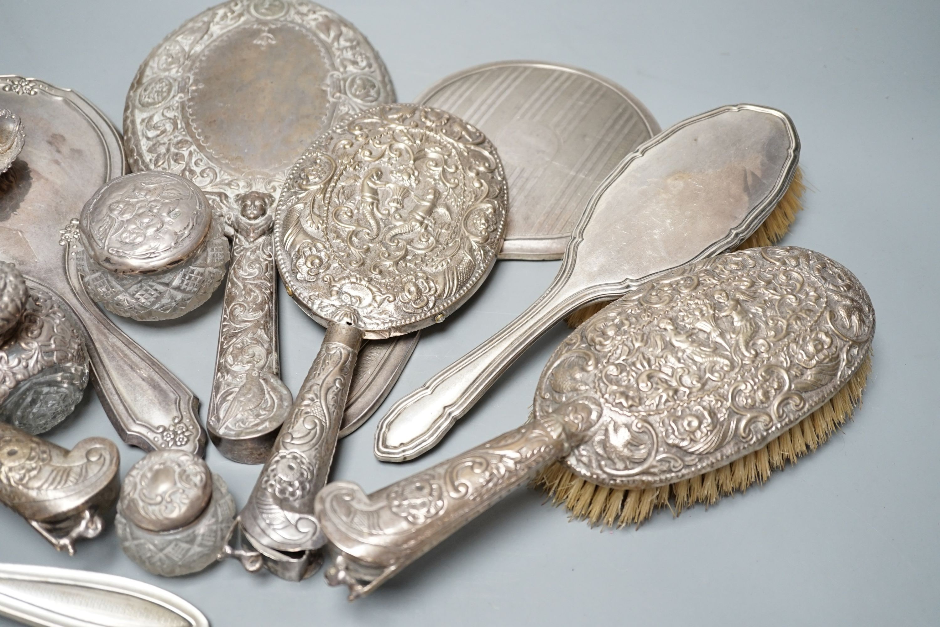 A mixed collection of four silver mounted vanity mirrors, four assorted clothes brushes, (including set of three), three silver mounted glass jars and a small silver dish.